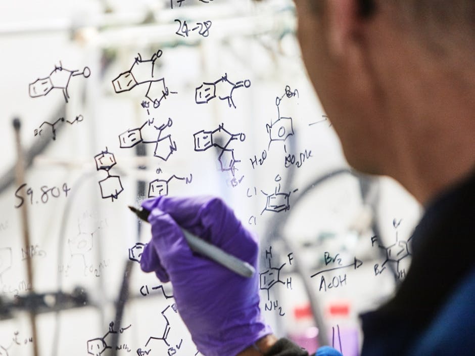 Researcher drawing molecules on whiteboard