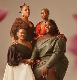 a group of four black women in elegant attire posing for a group portrait