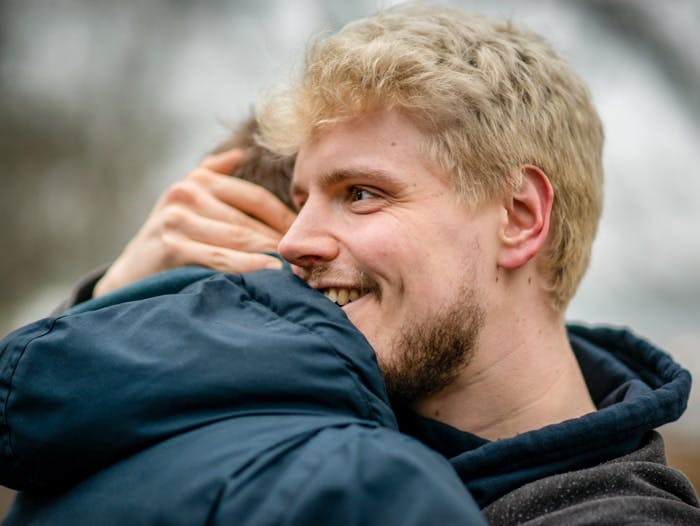 Homme blond en bonne santé vivant avec le VIH et serrant son ami contre lui dans un parc à Hambourg, Allemagne