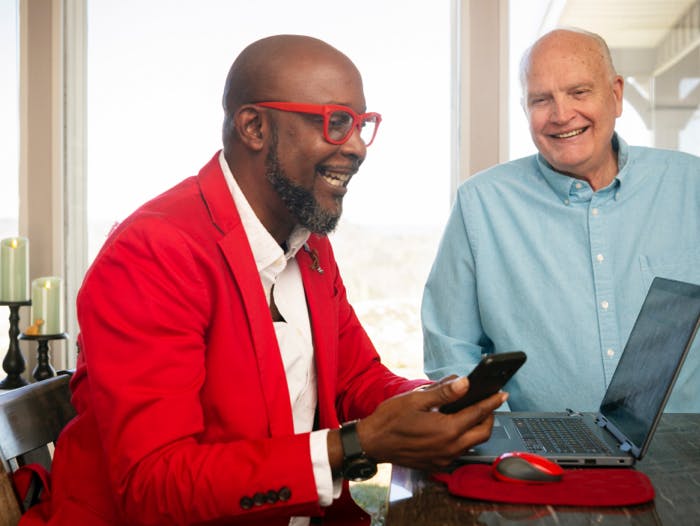 Homme noir vivant avec le VIH, travaillant de chez lui sur son ordinateur portable, en compagnie de son partenaire