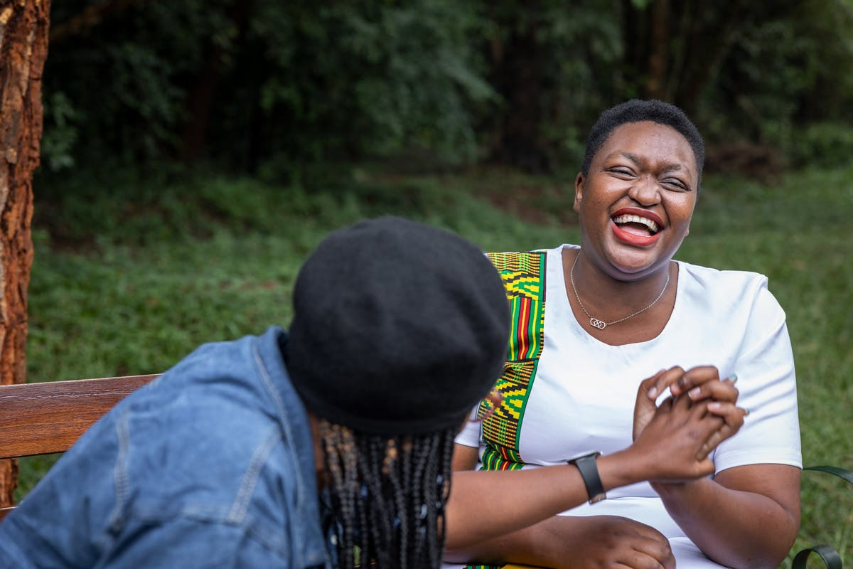 Deux amies en train de rire et discuter sur un banc à Nairobi, au Kenya. La femme à droite vit avec le VIH.