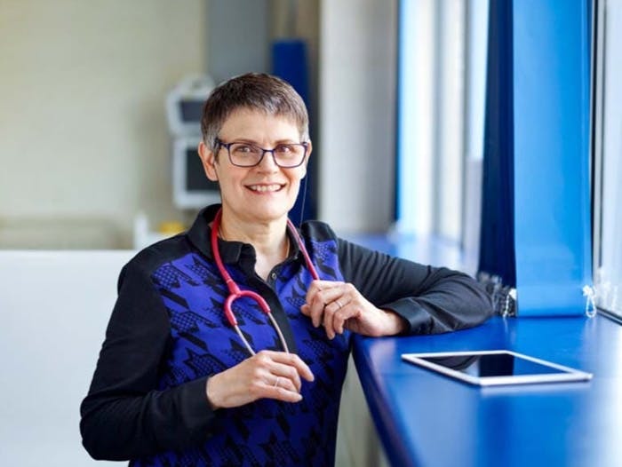 Operatrice sanitaria sorridente con stetoscopio e iPad